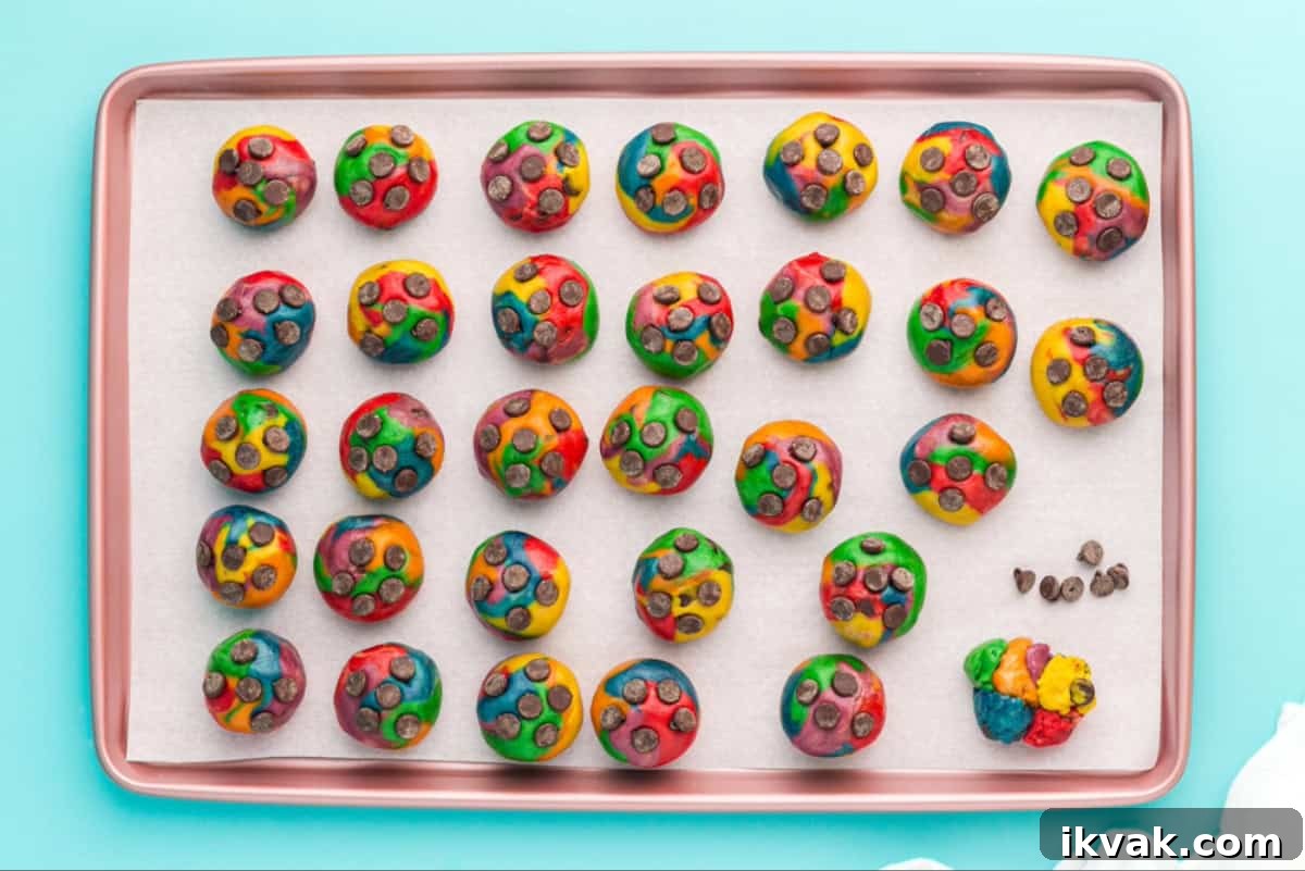 Tie-dyed cookie dough balls arranged on a baking sheet.