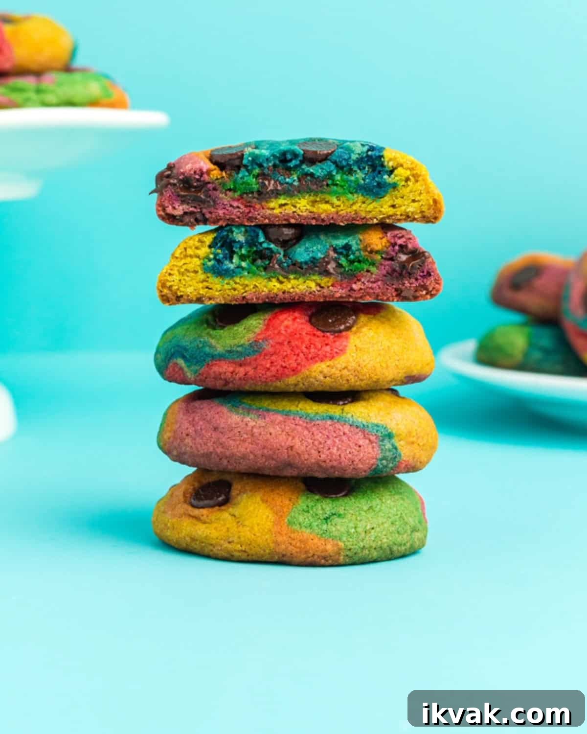 A stack of rainbow chocolate chip cookies against a neon blue background.