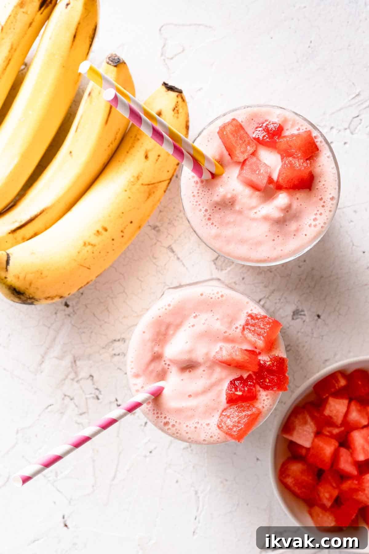 Creamy Banana and Watermelon Smoothie Recipe 9 two smoothies garnished with chunks of watermelon with bananas and bowl of watermelon on the side