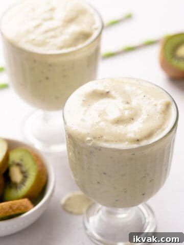 two glasses of smoothie with straws and kiwi on the side