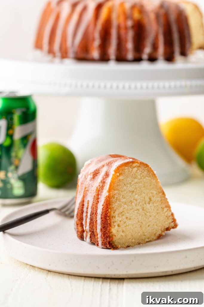 Moist 7-Up Pound Cake | Southern Soul Food Recipe 2 slice of 7-up pound cake on a white plate with a can of 7-up, lemon, lime and whole cake in the background