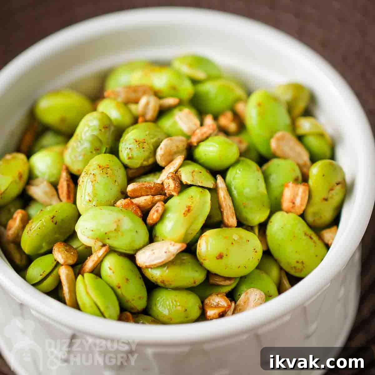 Side view of chipotle edamame in a white bowl with a brown background.
