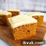 Pumpkin spice cakes with cream cheese frosting on a chopping board.