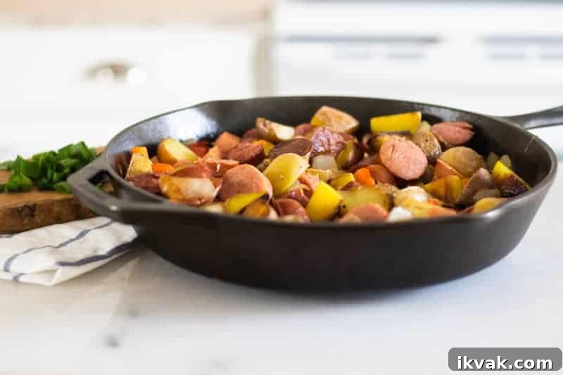 sausage, potatoes and onions chopped up in a cast-iron skillet on marble table top