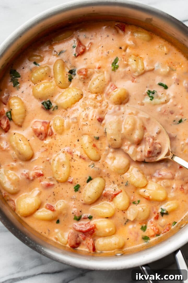 Creamy Tomato Gnocchi Recipe: Quick Weeknight Comfort Meal 6 a skillet with creamy tomato gnocchi and a serving spoon