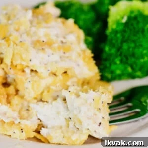 A bite of chicken on a fork from Poppy Seed Chicken Casserole. Broccoli is on the plate in the background