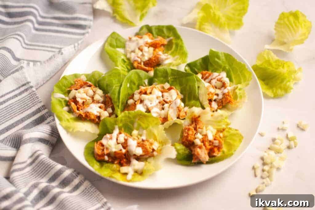 A white plate with six Buffalo Chicken Lettuce Wraps placed next to a striped towel.
