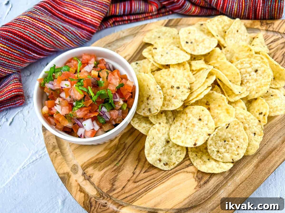 A shot of Pico de Gallo on a board with chips nearby.