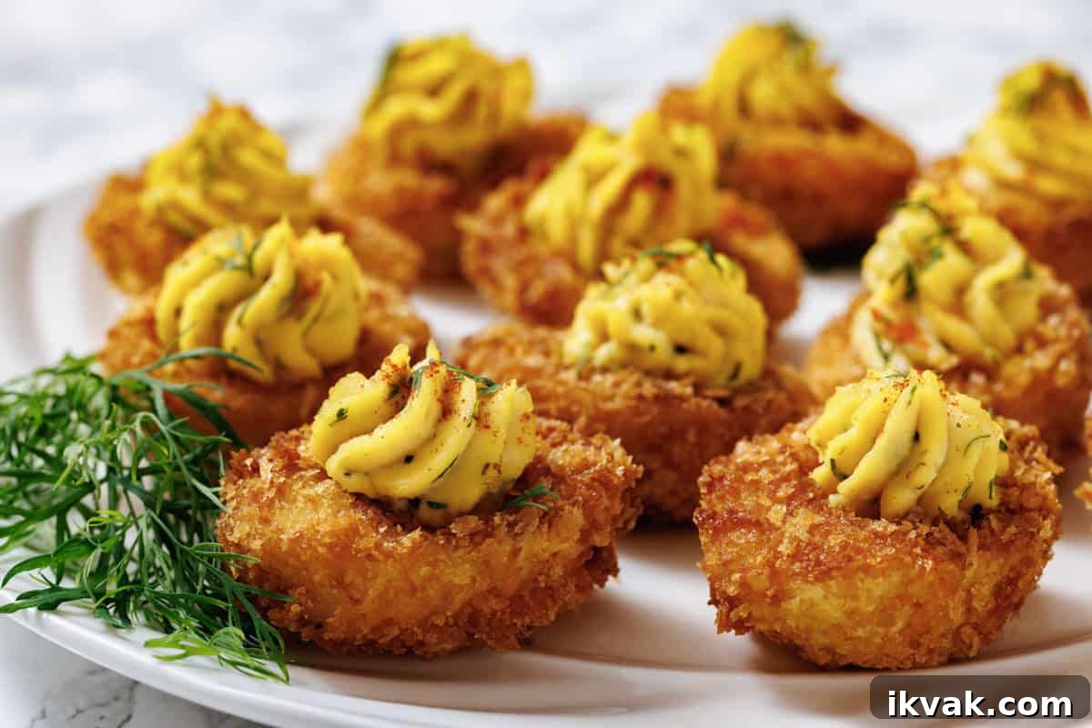 A close-up shot of fried deviled eggs on a white plate, with a focus on the texture and garnish.