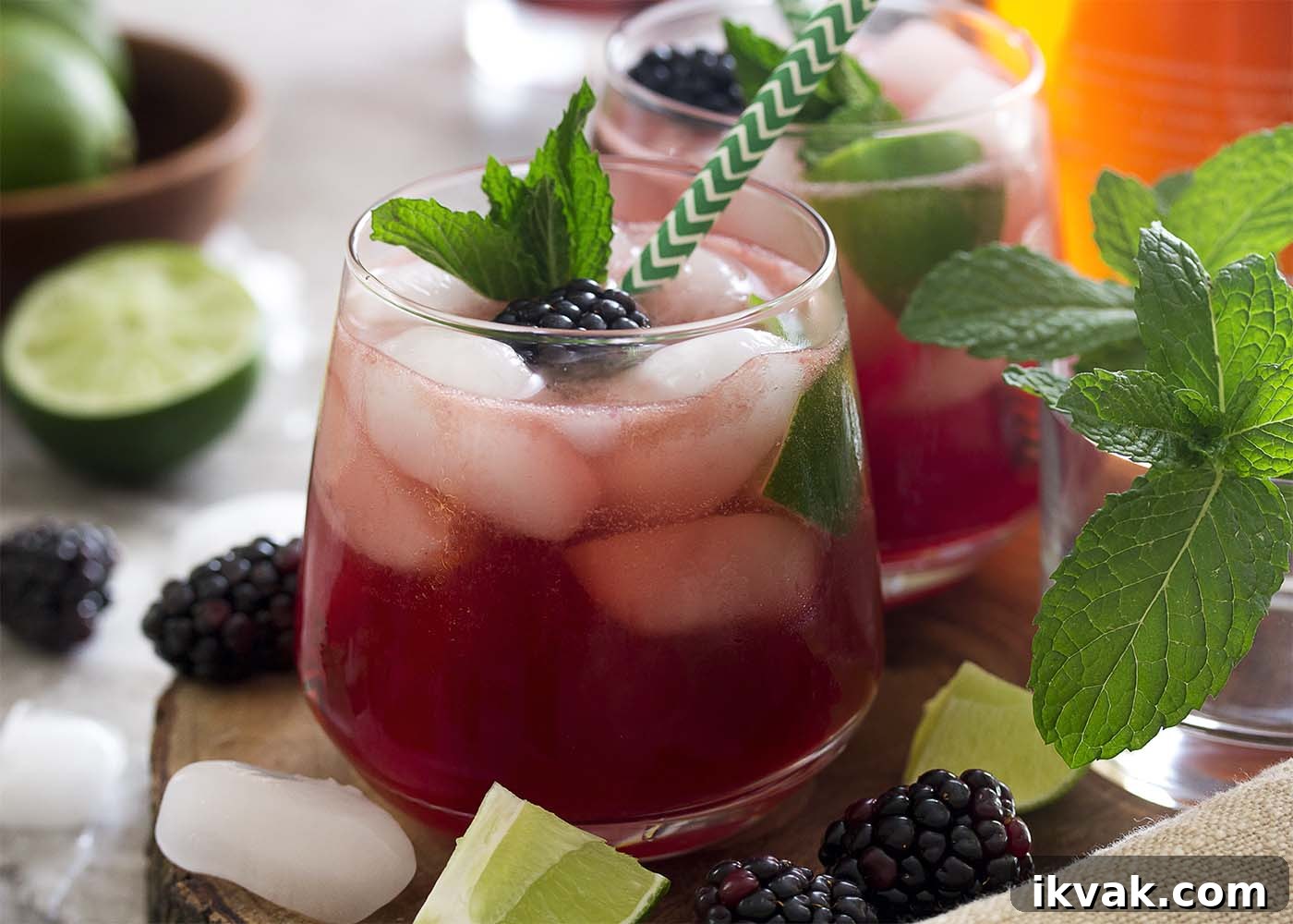 Blackberry Mojito Recipe: A Refreshing Summer Cocktail Guide 3 Side view of a blackberry mojito with a straw in the glass. Blackberries and lime scattered about.