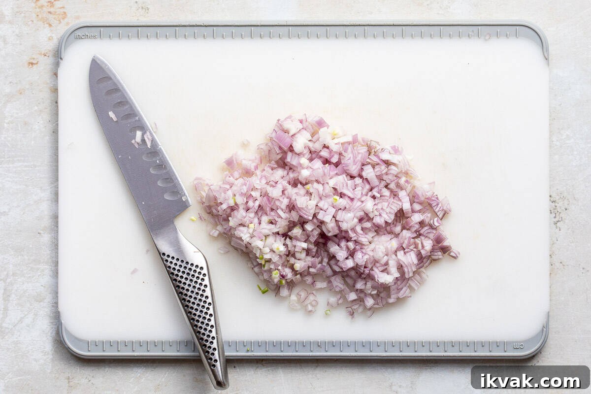Classic Maryland Cream of Crab Soup Recipe 5 chopped shallots on cutting board with knife.