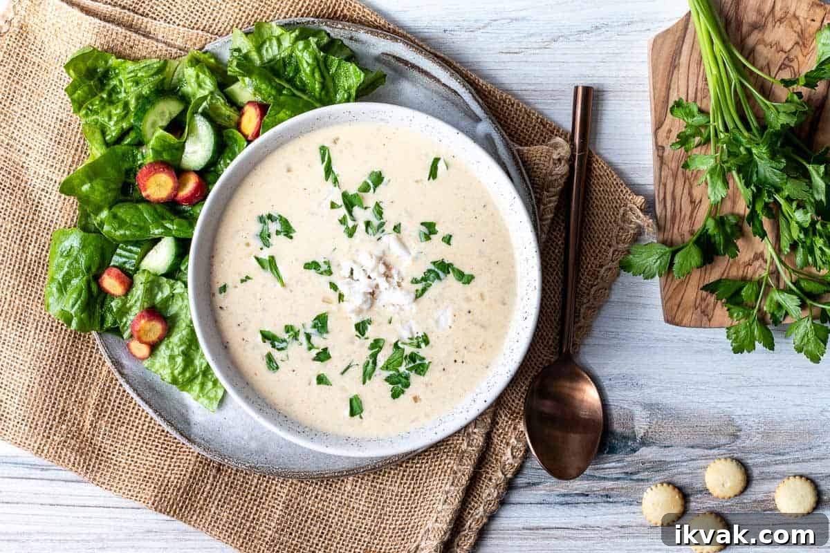 Classic Maryland Cream of Crab Soup Recipe 9 bowl of cream of crab soup next to green salad and spoon.