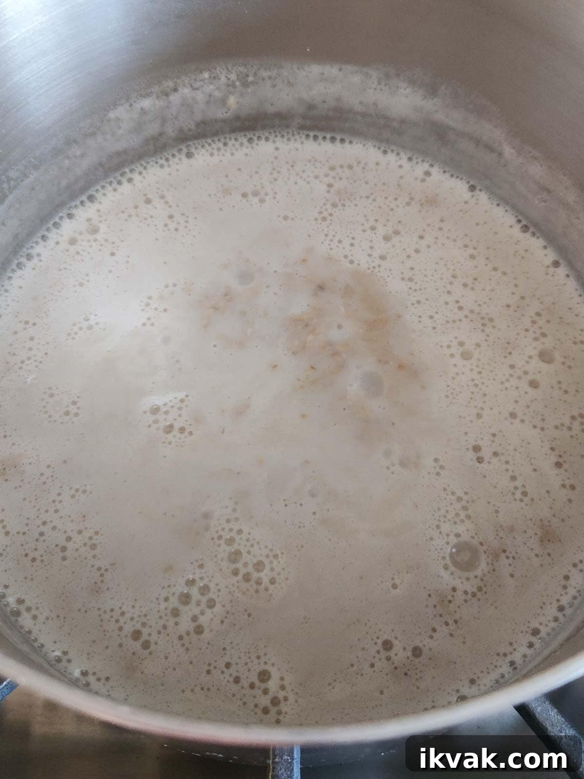 Creamy Scottish Oatmeal with Dates and Honey 5 Oatmeal cooking in a stainless steel pot.