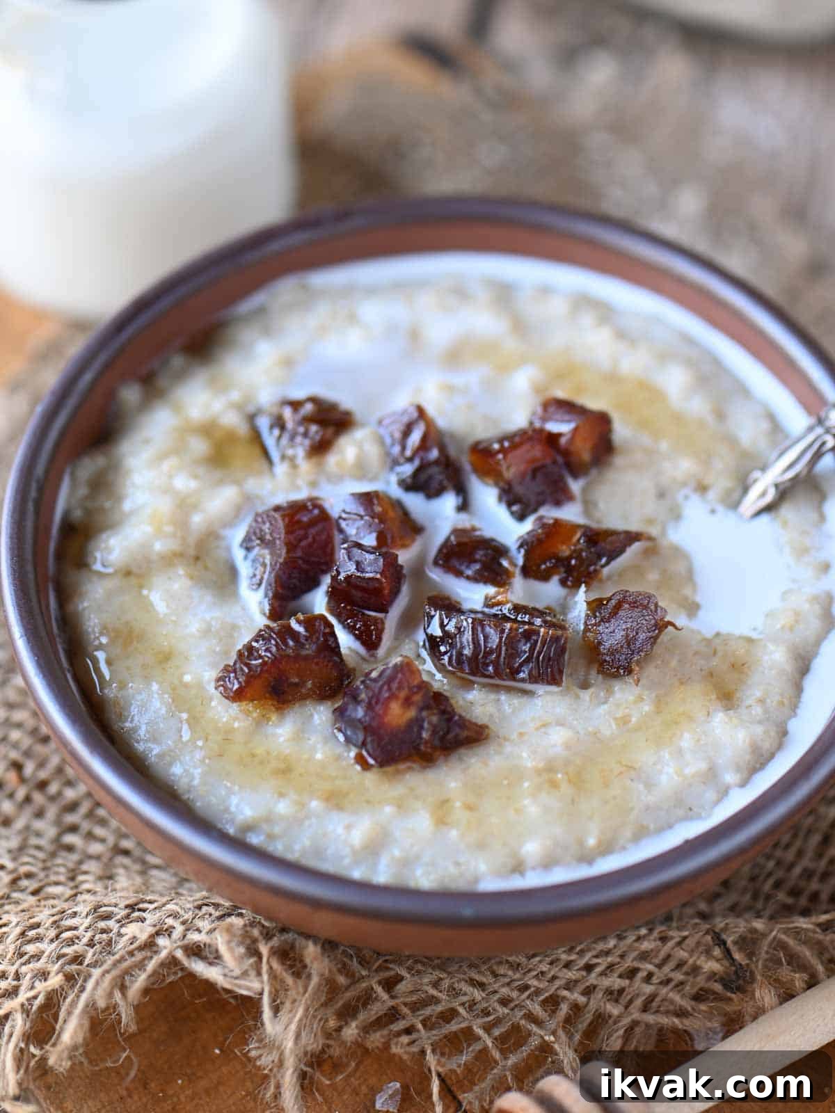 Creamy Scottish Oatmeal with Dates and Honey 7 Angled view of oatmeal in a brown bowl with dates on top.