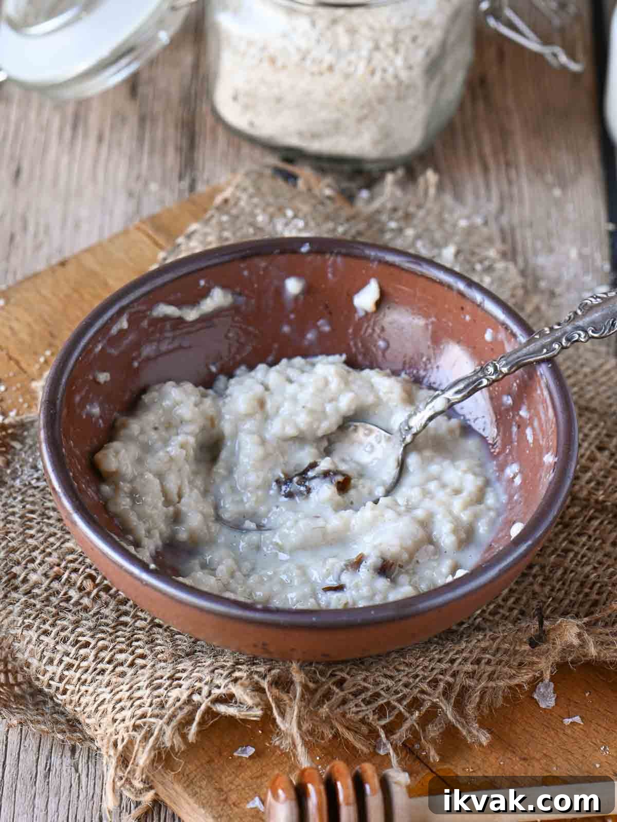 Creamy Scottish Oatmeal with Dates and Honey 8 Half eaten bowl of oatmeal in a brown bowl with a spoon the right.
