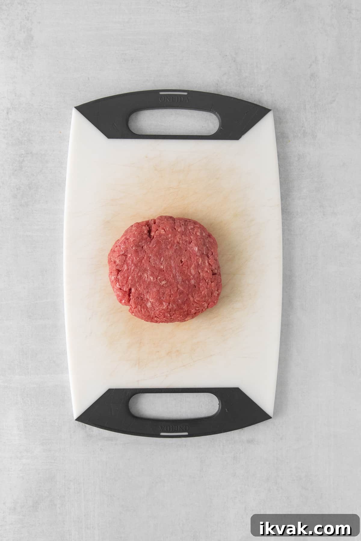 Raw beef patty on a cutting board.
