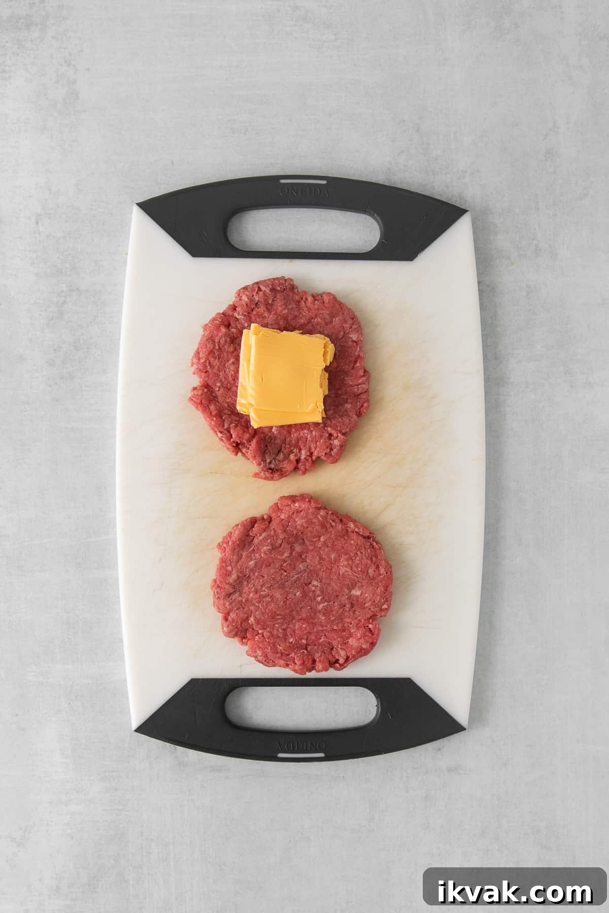 Raw beef patty with a square of american cheese on it.