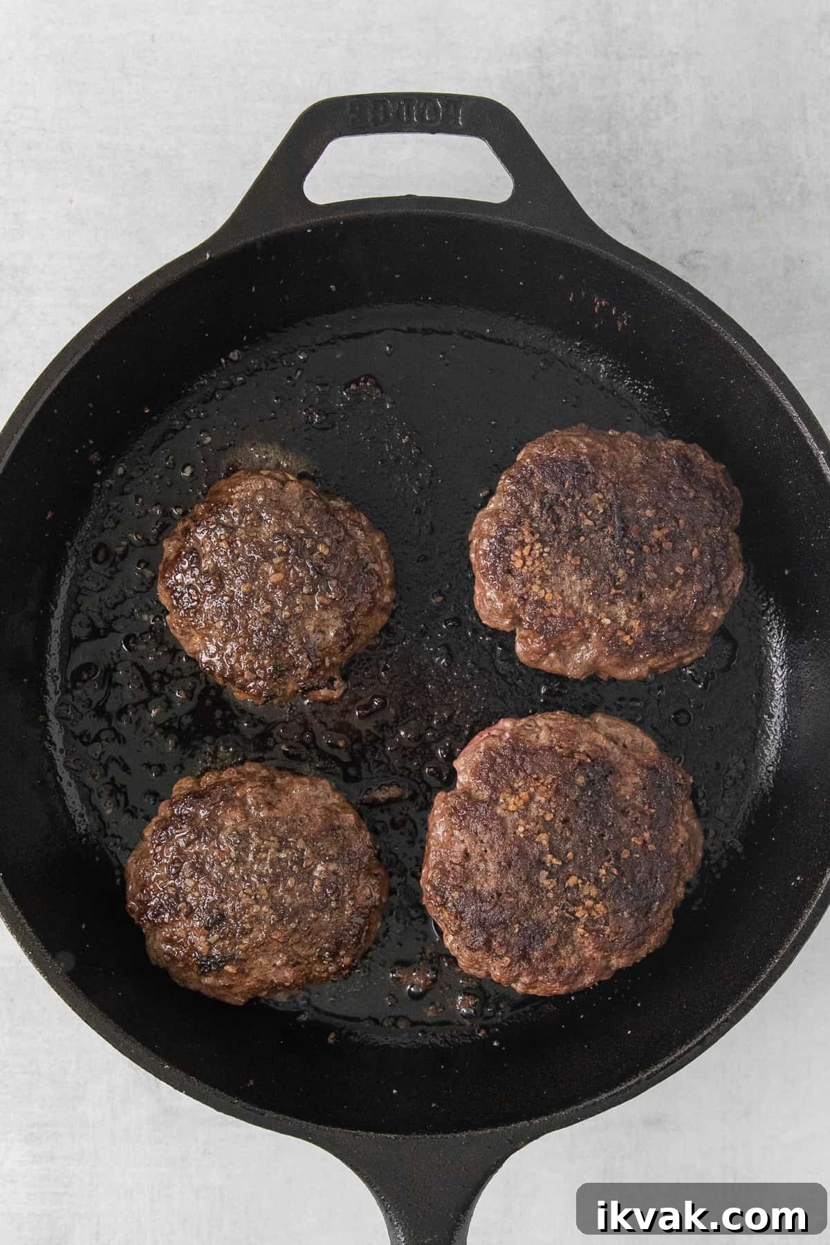 Juicy lucy burgers in a cast iron skillet.