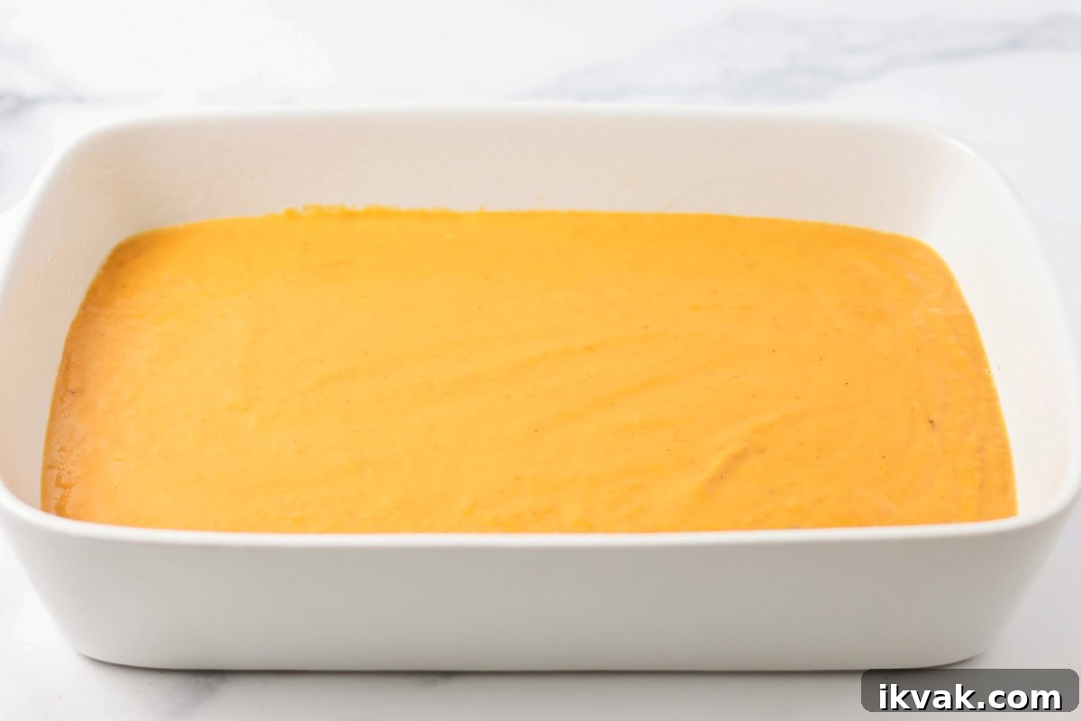 Pumpkin mixture spread in a baking dish for pumpkin cobbler recipe.