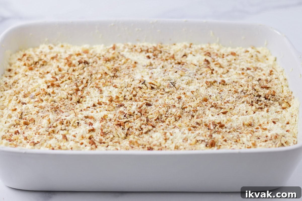 Pumpkin cobbler topped with pecans and ready to be baked.