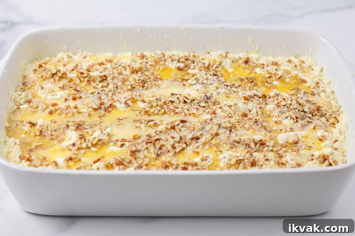 Topping pumpkin cobbler with pecans and melted butter.