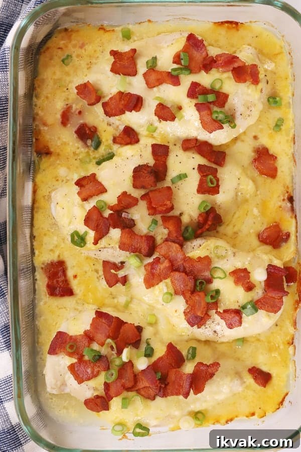 Baked chicken with mustard and bacon bits in a baking dish.