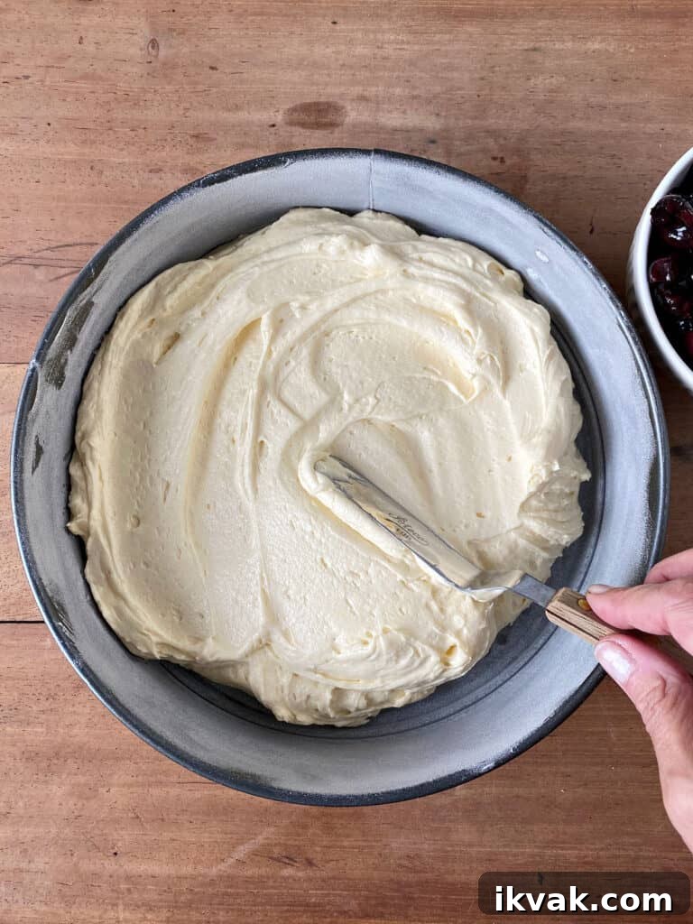 Moist Cherry Cake with Fresh Cherry Glaze 6 Spreading cake batter on round cake pan. Wooden surface.