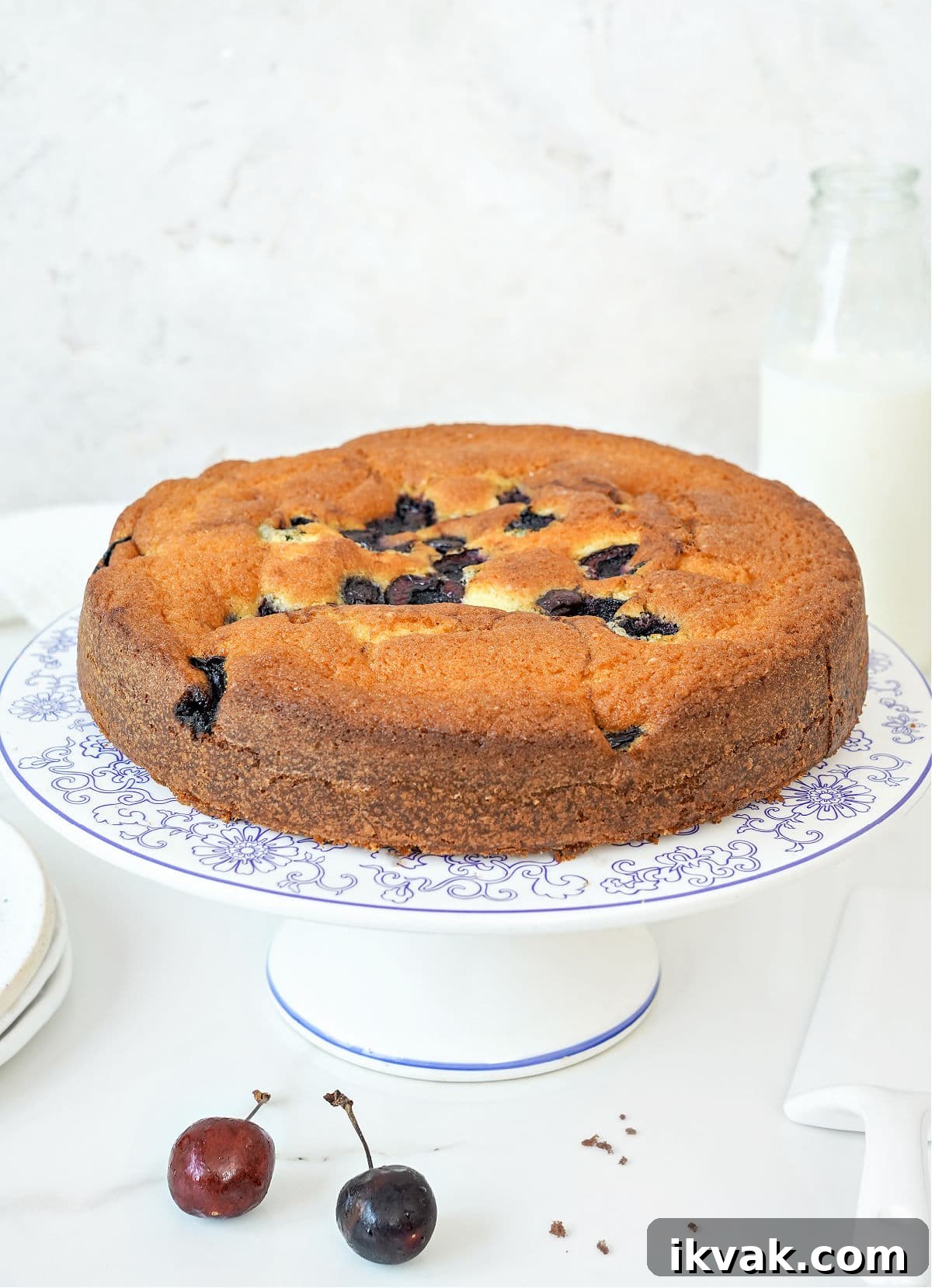 Moist Cherry Cake with Fresh Cherry Glaze 8 Whole plain cherry cake on a white cake stand. White background.