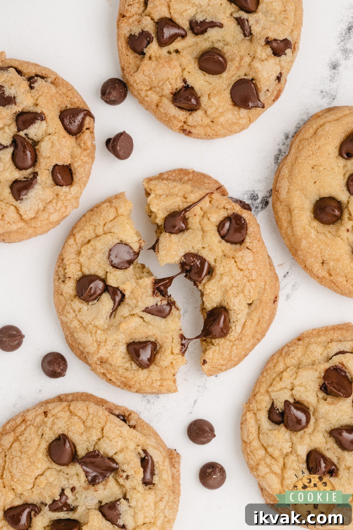 Close-up of a chocolate chip cookie torn in half showing gooey, melty chocolate chips and a soft, chewy center.