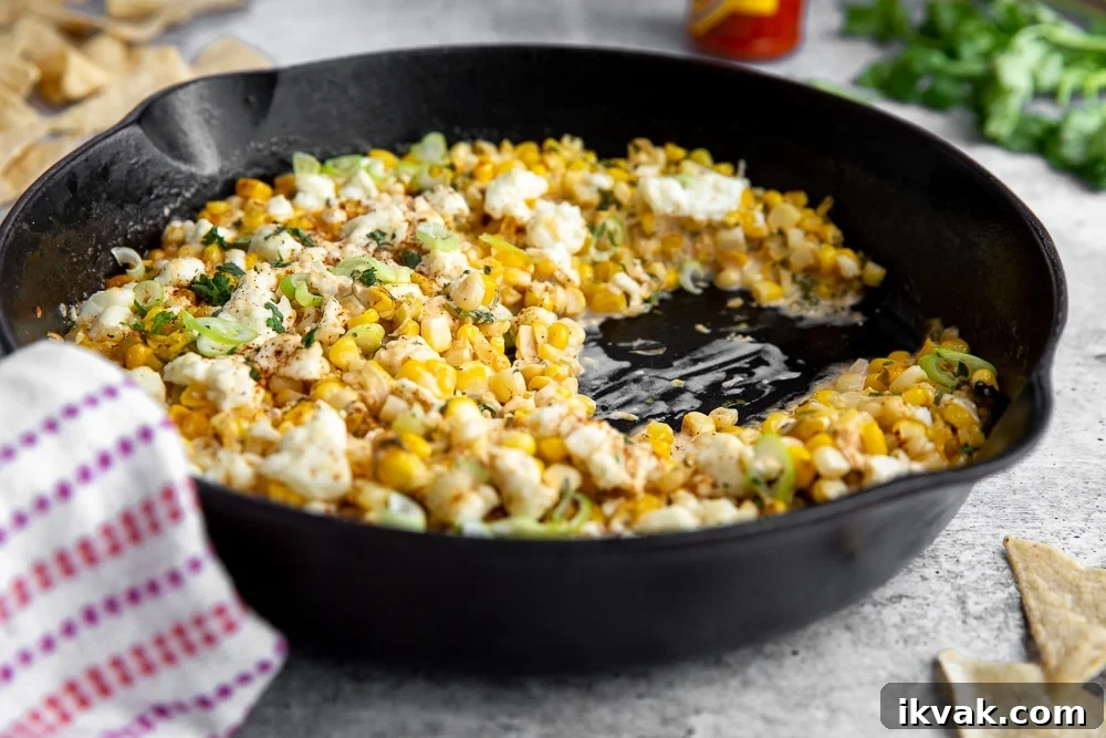 Side angle shot of Mexican street corn dip in cast iron skillet. 
